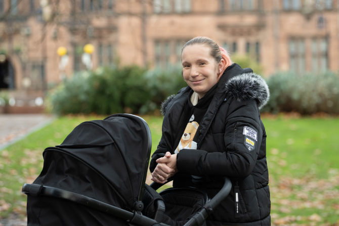 Image of a lady outside stood next to a pram