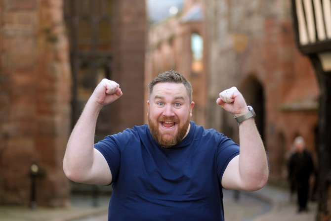 Image of man outside with two fists in the air like a celebration